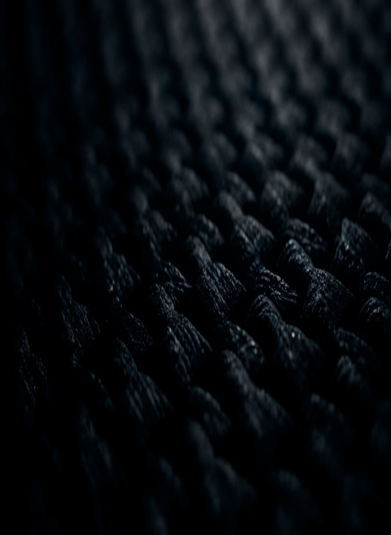 Dark close-up textured surface with repeating organic ridges fading into shadow, creating a dramatic abstract background.