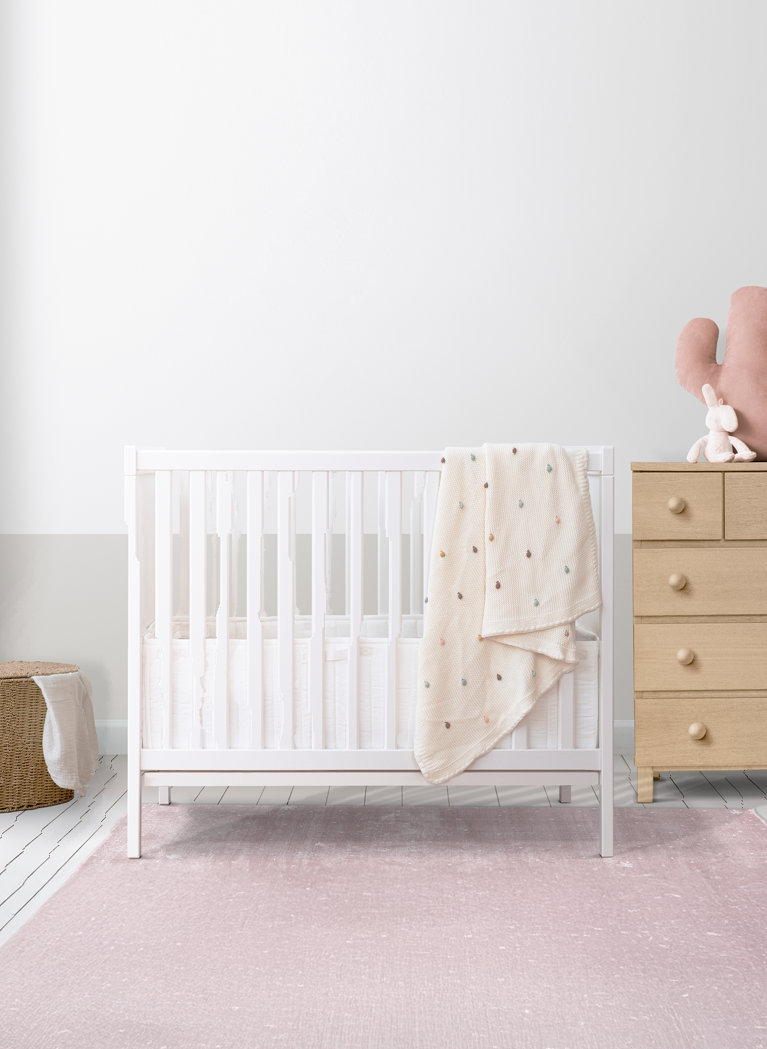 Baby nursery photograph with a cot and dresser