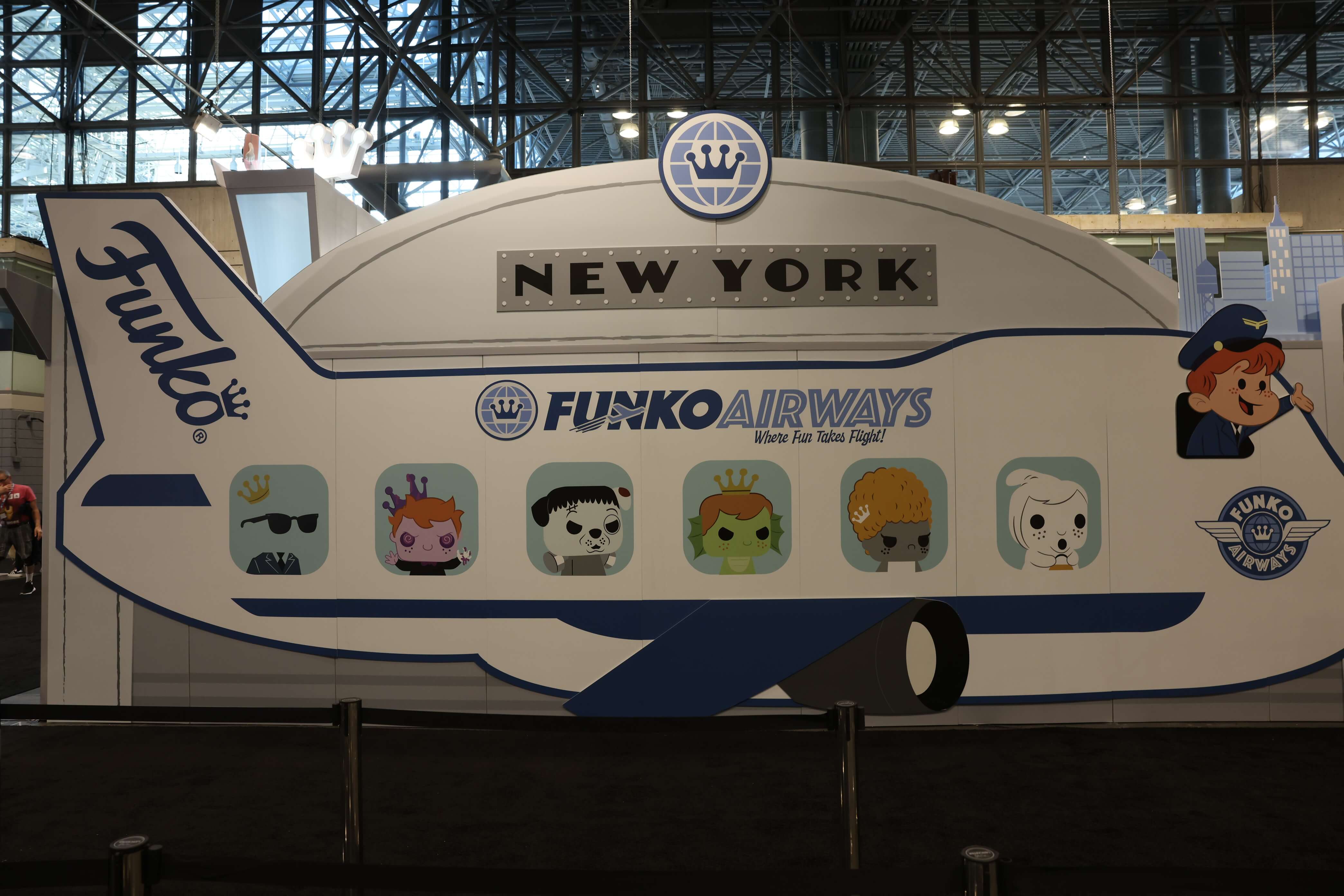 Funko Airways booth with a cutout of a plane with Freddy Funko flying--Franny, Proto, and Eddy are there in the windows, looking frightful in costumes.