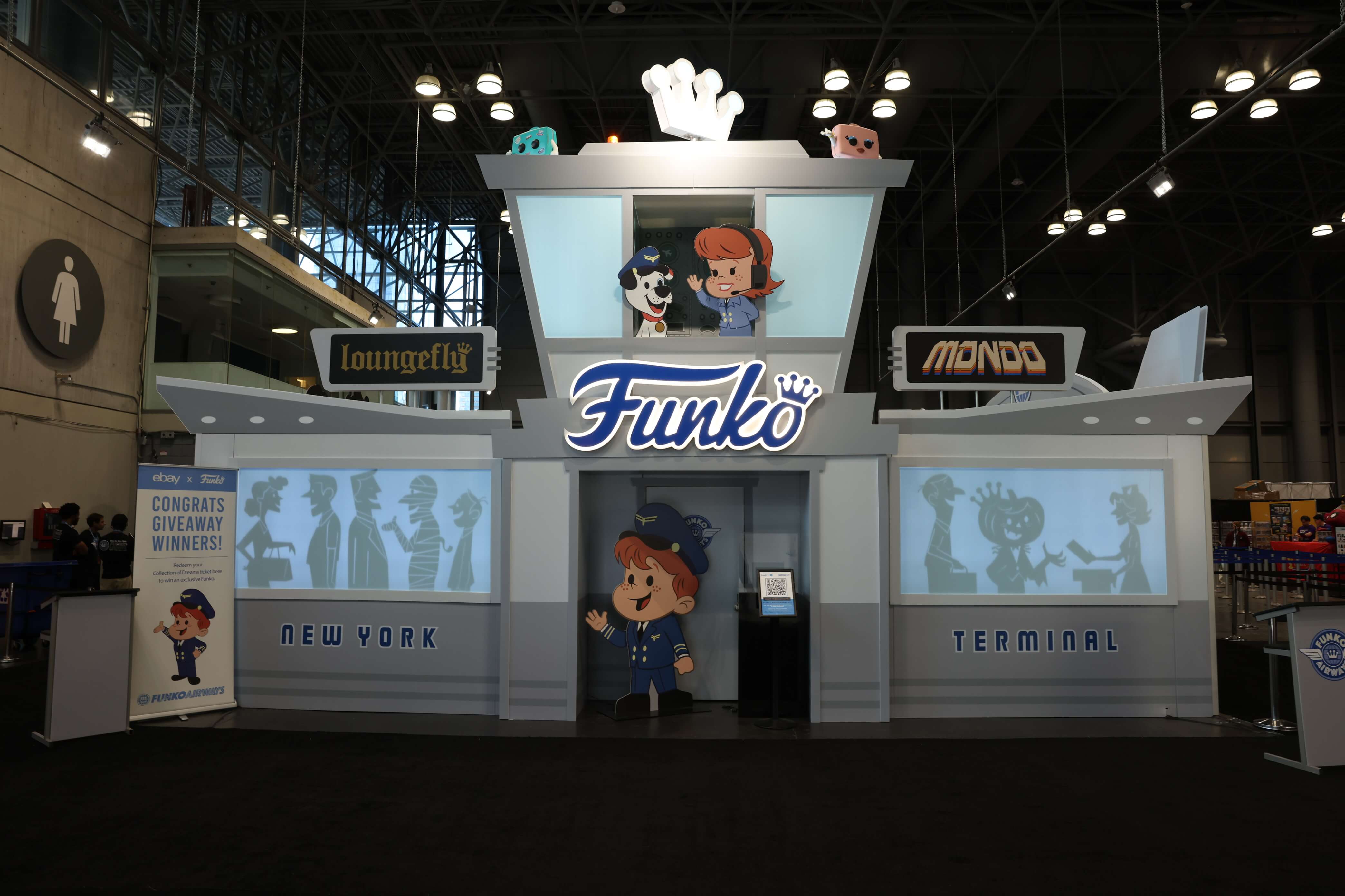 Airport-themed Funko Airways booth featuring cutouts of Freddy Funko and friends dressed in pilot/flight crew attire.