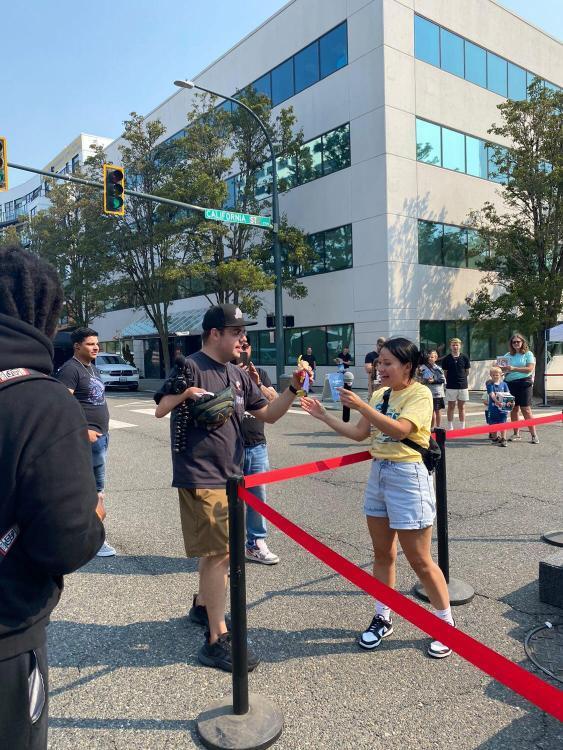Line Up: A Funko volunteer in a Fun Fest 2023 yellow tee shirt helps distribute prizes and announce winners at the DJ stage/booth.