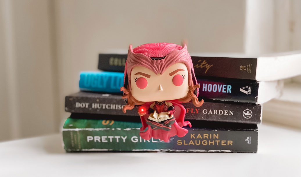 The Scarlet Witch levitating in front of a stack of books