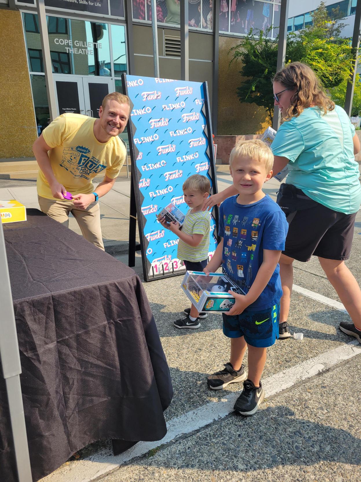 Flinko: Children try their hand at a Flinko game, while a Funko volunteer helps staff the tent.