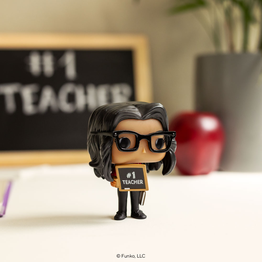 Pop! Yourself Teacher vinyl figure wearing glasses and holding a #1 Teacher chalkboard sign. Classroom, desk, and apple, are in the background